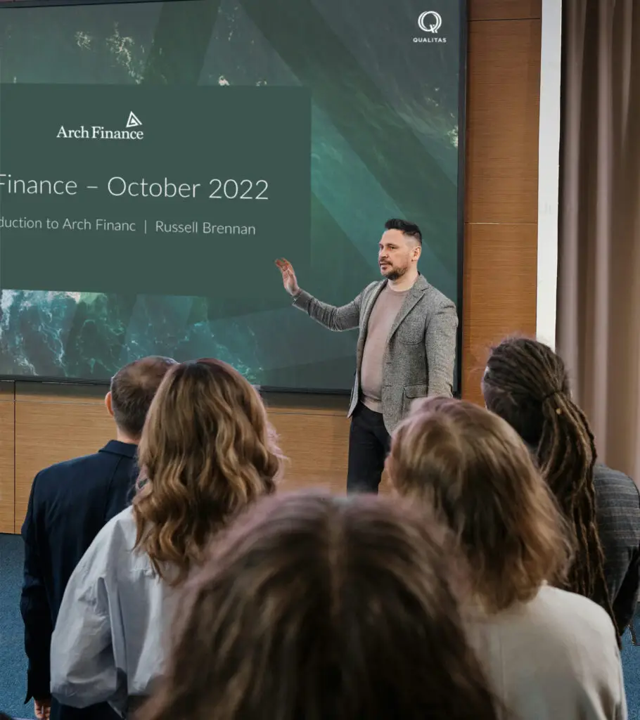 A presenter addresses a group of investors during a finance presentation, utilizing financial data visualization to attract and retain investors